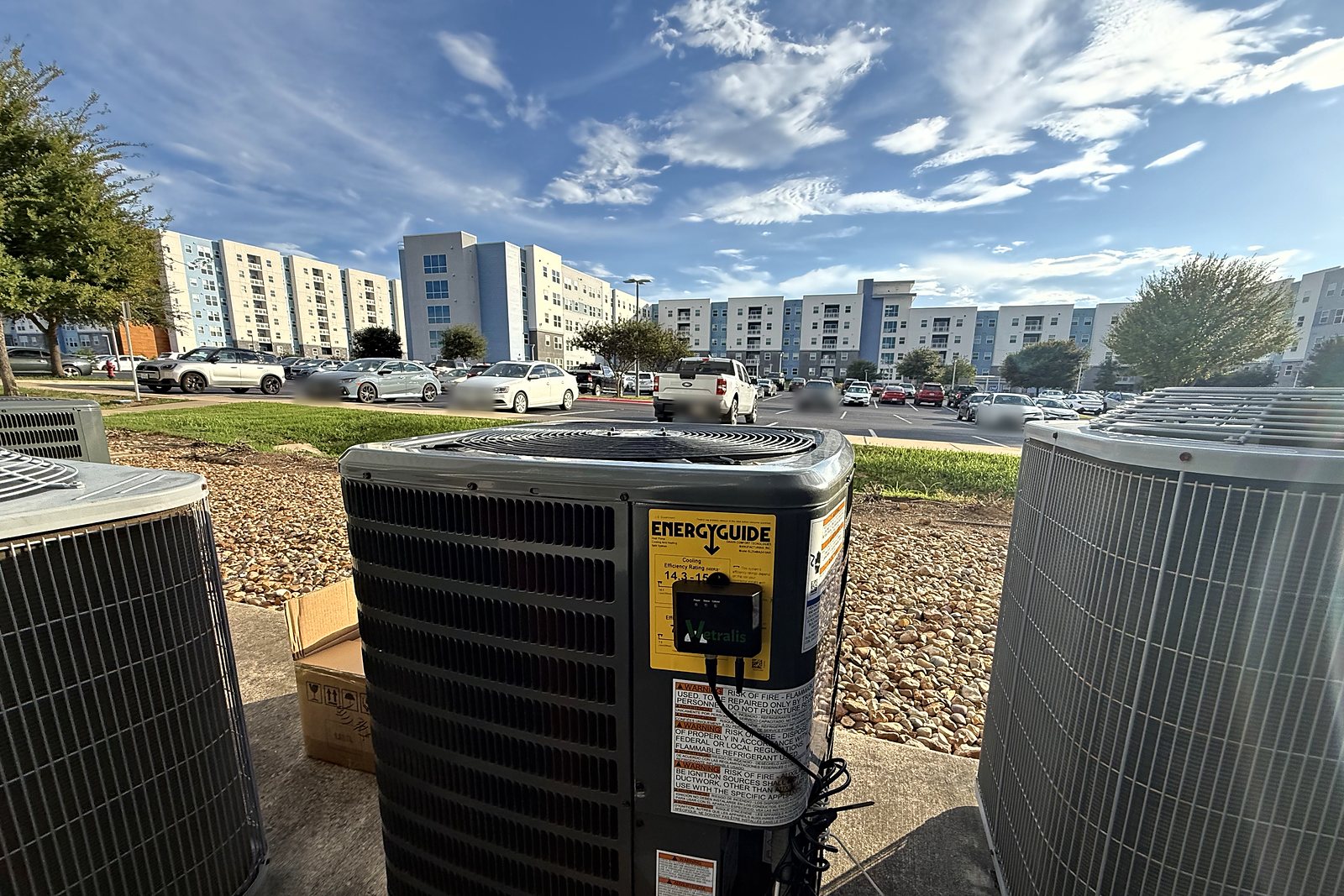 A ground-level condenser fitted with a Vetralis monitor, with Park West apartment buildings behind it