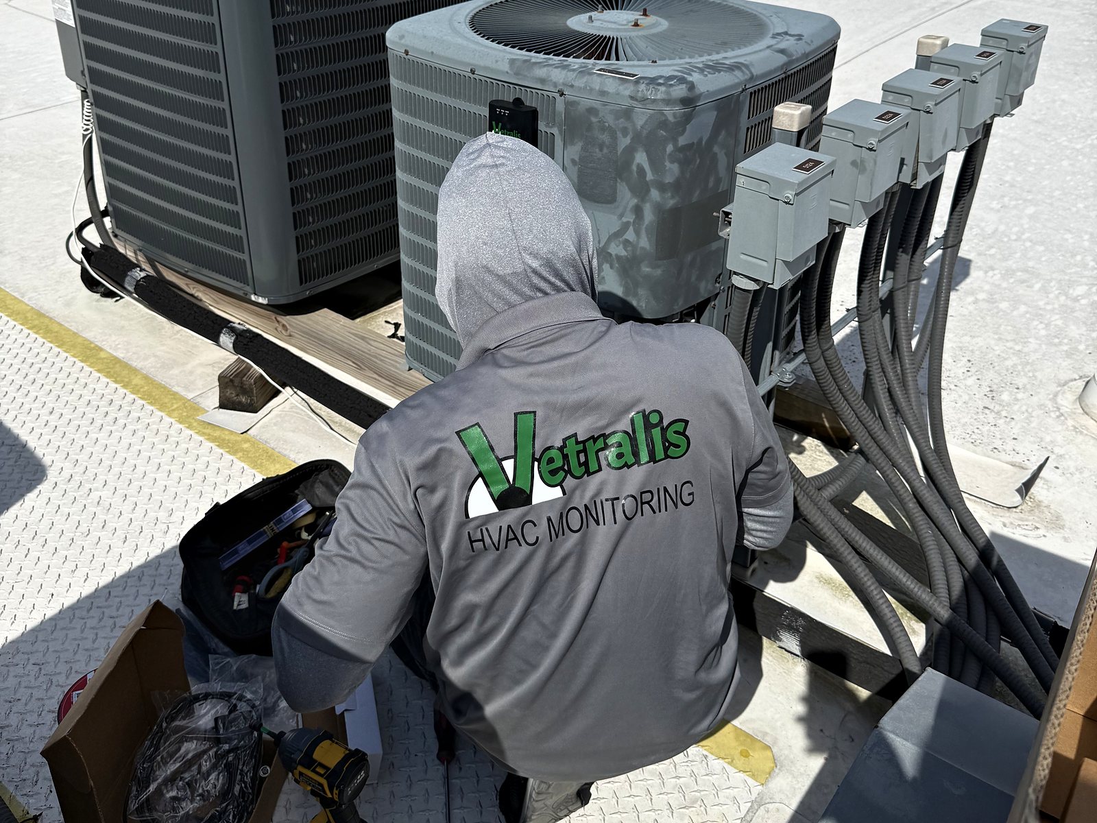 A Vetralis technician installing a monitor on a rooftop condenser